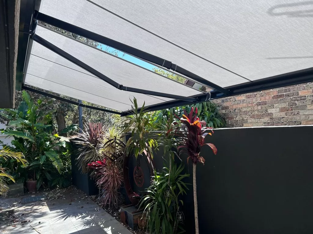 retractable awning extended over patio area with plants along the fenceline
