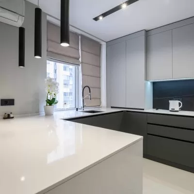 Elegant white and grey luxury kitchen, dining room with kitchen bar and stools in studio apartment interior